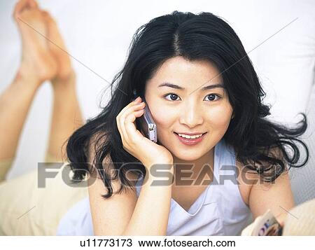 Stock Image - Image of a Young Adult Woman Talking on the Cell Phone, Smiling, Front View, Differential Focus. Fotosearch