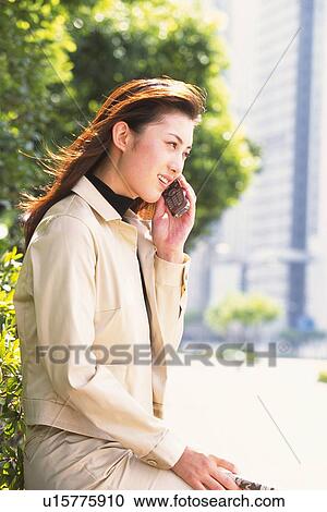Image of a Young Adult Woman Talking on her Cell Phone Outside, Side View, Differential Focus View Large Photo Image Stock Image - Image of a Young Adult Woman Talking on her Cell Phone Outside, Side View, Differential Focus. Fotosearch