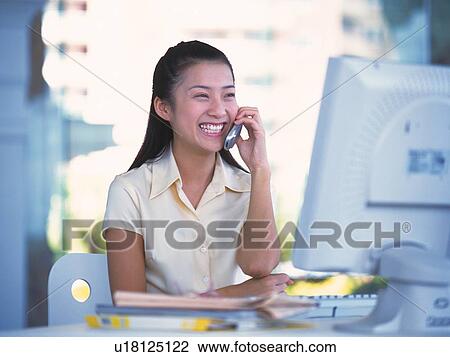 Image of a Young Adult Woman Talking on the Phone In Front of a Computer, Smiling, Side View, Differential Focus View Large Photo Image Stock Image - Image of a Young Adult Woman Talking on the Phone In Front of a Computer, Smiling, Side View, Differential Focus. Fotosearch