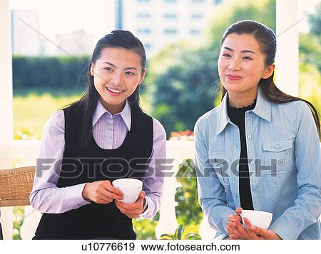 Image of Two Young Adult Woman Having a Cup of Coffee, Smiling? Looking Sideways, Front View View Large Photo Image Stock Photo - Image of Two Young Adult Woman Having a Cup of Coffee, Smiling? Looking Sideways, Front View. Fotosearch