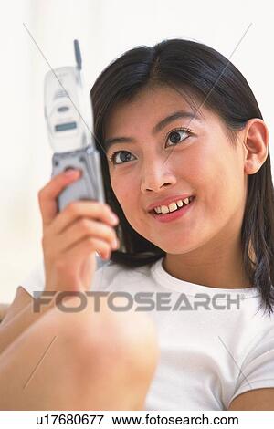 Stock Photo - Japanese woman holding mobile phone. Fotosearch
