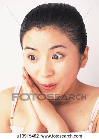 Stock Image - Japanese woman looking down and being surprised. Fotosearch
