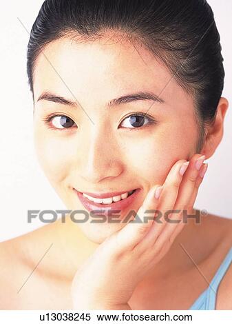 Stock Photography - Japanese woman resting her chin on hand, smiling to camera. Fotosearch