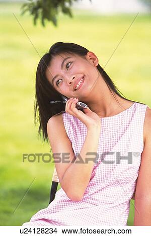 Picture - Japanese woman using mobile phone, inclining head. Fotosearch
