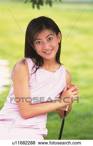 Stock Photo - Portrait of Japanese woman smiling and leaning on chair. Fotosearch