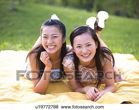 Stock Photo - Portrait of two women lying on stomach, smiling. Fotosearch
