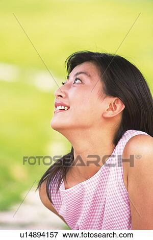 Stock Photo - Profile of Japanese woman looking up in green field. Fotosearch