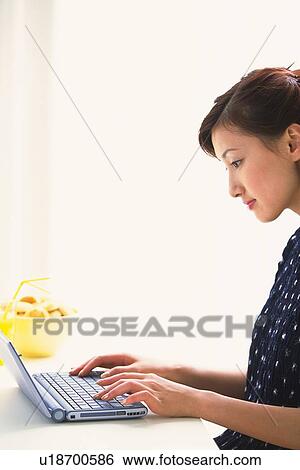 Stock Photograph - Profile of woman using a laptop. Fotosearch