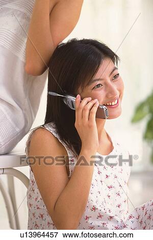 Two woman, one using mobile phone View Large Photo Image Stock Photo - Two woman, one using mobile phone. Fotosearch