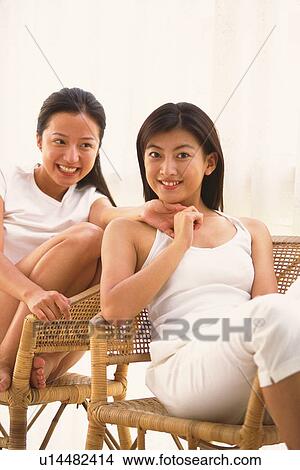 Picture - Two women sitting on chair, portrait of one who holding the hand of the other. Fotosearch