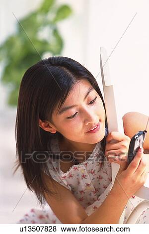 Woman bending down and using mobile phone View Large Photo Image Stock Photo - Woman bending down and using mobile phone. Fotosearch
