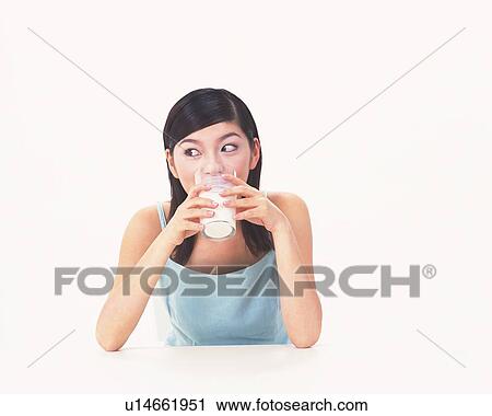 Stock Image - Woman drinking milk, putting elbows on table. Fotosearch