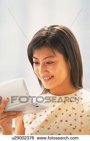 Stock Photograph - Woman holding and looking at PDA. Fotosearch