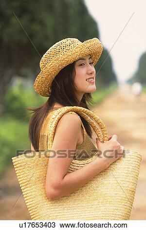 Stock Image - Woman in straw hat, looking back. Fotosearch