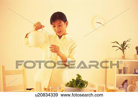 Woman pouring glass of water from jug at kitchen View Large Photo Image Stock Photo - Woman pouring glass of water from jug at kitchen. Fotosearch