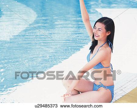Woman raising arm and sitting at the side of the pool View Large Photo Image Stock Image - Woman raising arm and sitting at the side of the pool . Fotosearch