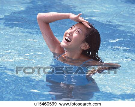Stock Photo - Woman shielding eyes from the sun in the pool . Fotosearch