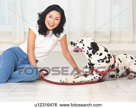 Stock Photograph - Woman sitting on floor with a dog, looking at camera. Fotosearch