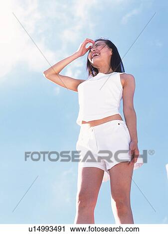 Stock Image - Woman standing with a smile under the blue sky. Fotosearch