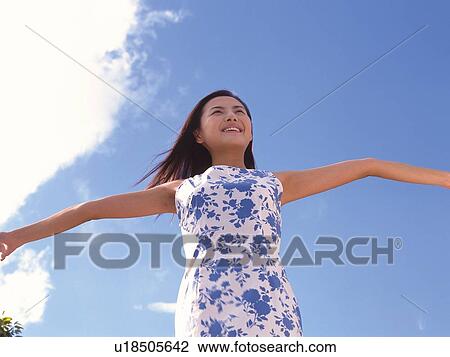 Woman stretching arms out under the blue sky View Large Photo Image Stock Image - Woman stretching arms out under the blue sky. Fotosearch
