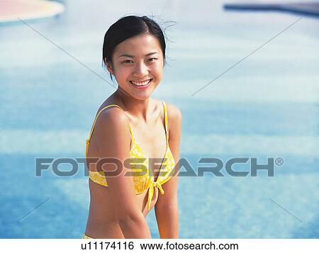 Stock Photograph - Woman wearing bikini, smiling at the side of the pool . Fotosearch