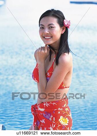 Stock Image - Woman wearing bikini, standing at the side of the pool . Fotosearch