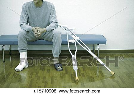 Man patient with cast on leg using crutches in exam room View Large Photo Image Stock Photo - Man patient with cast on leg using crutches in exam room . Fotosearch