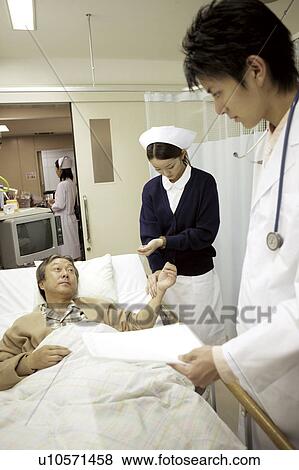 Nurse takes the pulse of a patient lying in a hospital bed View Large Photo Image Stock Photo - Nurse takes the pulse of a patient lying in a hospital bed . Fotosearch