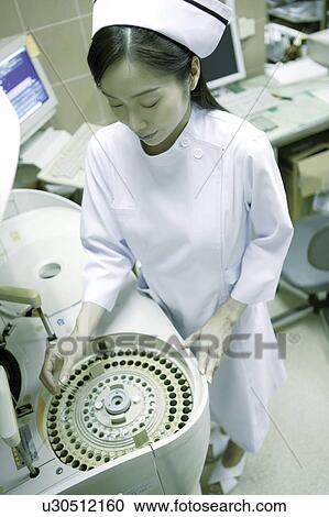 Stock Image - Nurse using a sterilization machine. Fotosearch