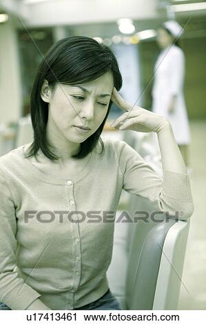 Stock Image - Woman holds her head as if suffering from a headache . Fotosearch