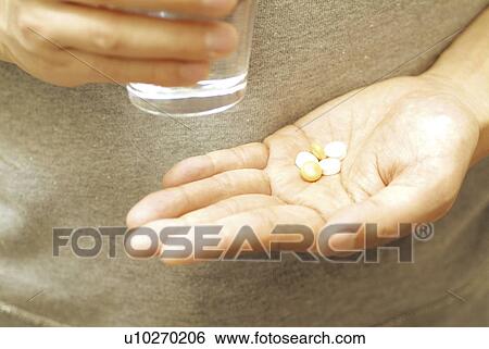 Woman taking a medicine, holding glass of water View Large Photo Image Stock Photograph - Woman taking a medicine, holding glass of water. Fotosearch