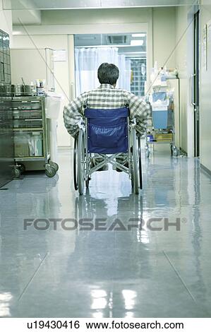 Stock Photograph - Young nurse talking to man patient in wheelchair . Fotosearch