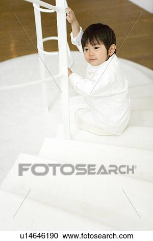 Stock Image - Photography of a boy sitting on the stairs, High Angle View. Fotosearch