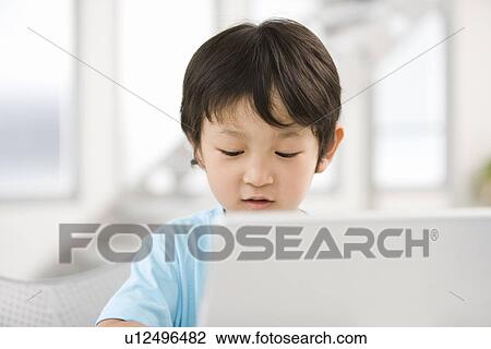 Stock Image - Photography of a boy using computer, Differential Focus. Fotosearch