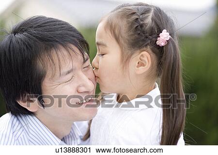 Stock Image - Photography of a daughter kissing father, Differential Focus. Fotosearch