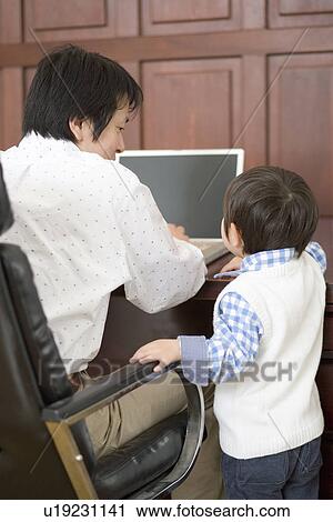 Stock Image - Photography of a father and son using computer, Low Angle View. Fotosearch
