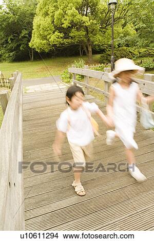 Picture - Photography of a girl and a boy crossing the wooden bridge, High Angle View, Blurred Motion. Fotosearch
