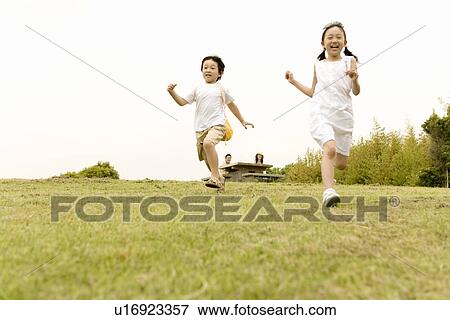 Stock Photo - Photography of a girl and a boy running in the park, Low Angle View. Fotosearch