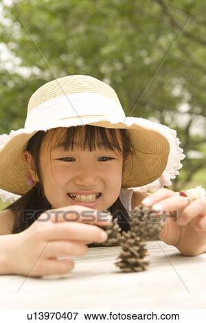 Stock Photo - Photography of a girl playing with pine cones, Differential Focus. Fotosearch