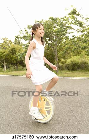 Stock Image - Photography of a girl riding an unicycle, Low Angle View. Fotosearch