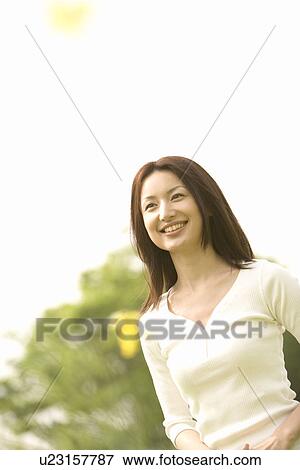 Stock Photo - Photography of a mid adult woman in the field, Low Angle View. Fotosearch