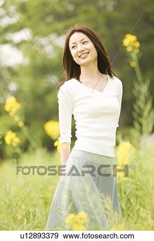 Stock Photo - Photography of a mid adult woman standing in the field, Differential Focus. Fotosearch