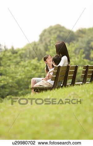 Stock Image - Photography of a mother and children sitting on the bench, Low Angle View. Fotosearch