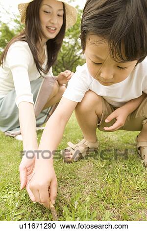 Stock Image - Photography of a mother and son playing in the park, Low Angle View. Fotosearch