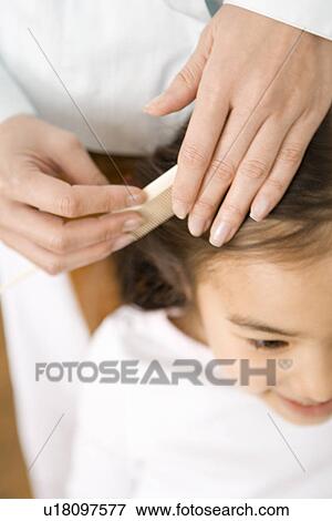 Stock Photo - Photography of a mother combing daughter's hair, High Angle View. Fotosearch