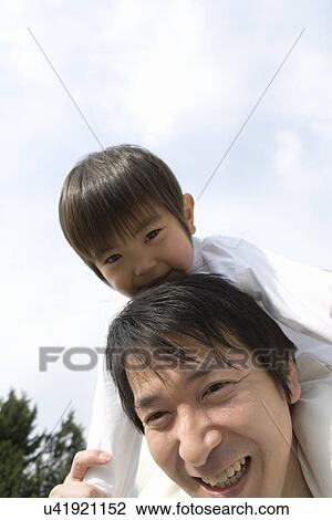 Stock Image - Photography of a son on father's shoulders, Low Angle View. Fotosearch