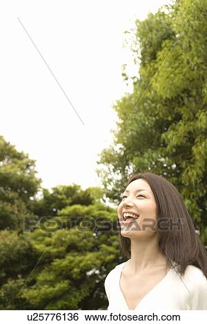 Stock Photograph - Photography of a woman smiling in the park, Low Angle View. Fotosearch