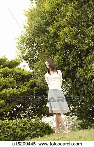 Stock Photography - Photography of a woman standing in the park, Low Angle View. Fotosearch