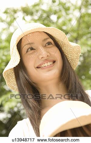 Photography of a woman with a straw hat smiling in the park, Low Angle View View Large Photo Image Stock Photo - Photography of a woman with a straw hat smiling in the park, Low Angle View. Fotosearch