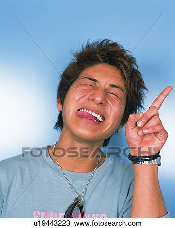 Stock Image - Portrait of Young Man Smiling, Sticking Out Tongue, Front View . Fotosearch